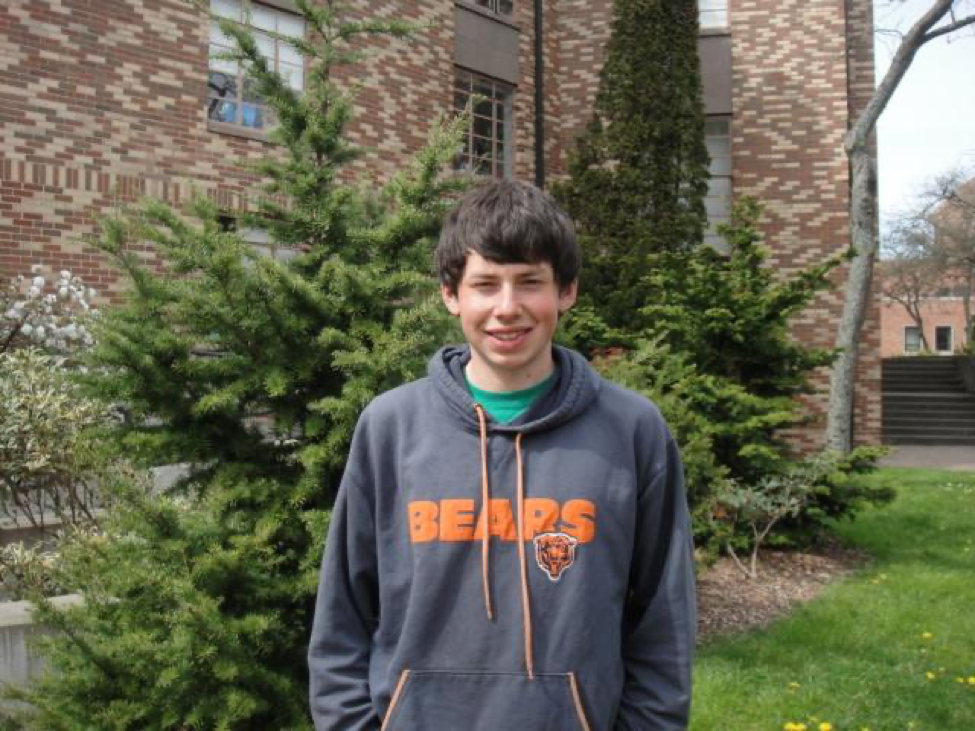 Portrait of Thomas wearing a Bears sweatshirt in front of College Hall.