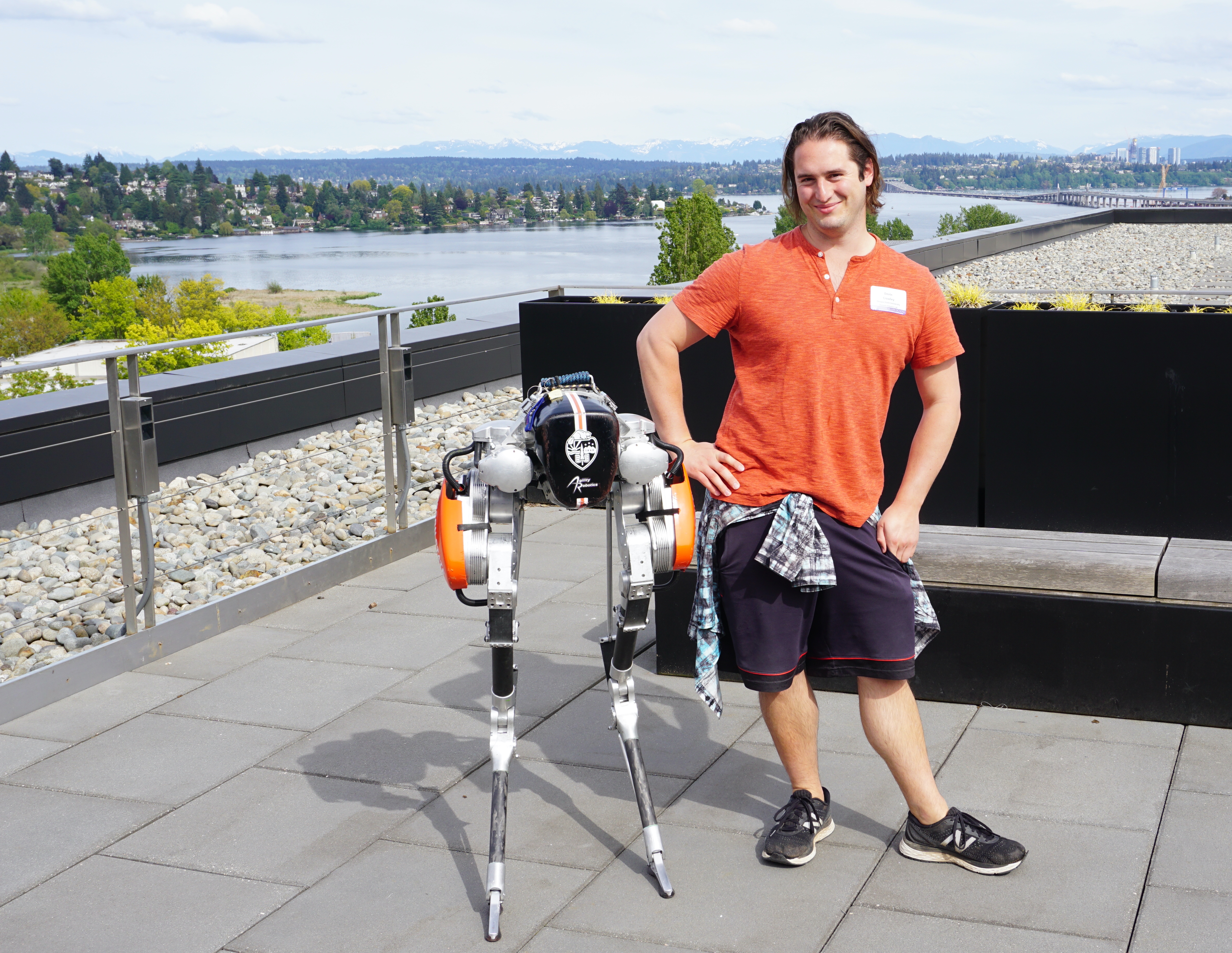 Honors alumni, Devin Crowley, stands outside next to the bipedal robot Cassie, built by Agility Robotics.