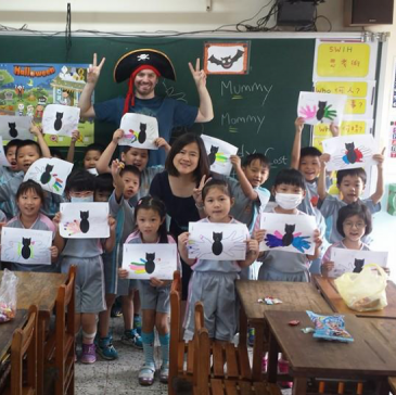 Tobias in a pirate hat poses with a classroom of children in Taiwan