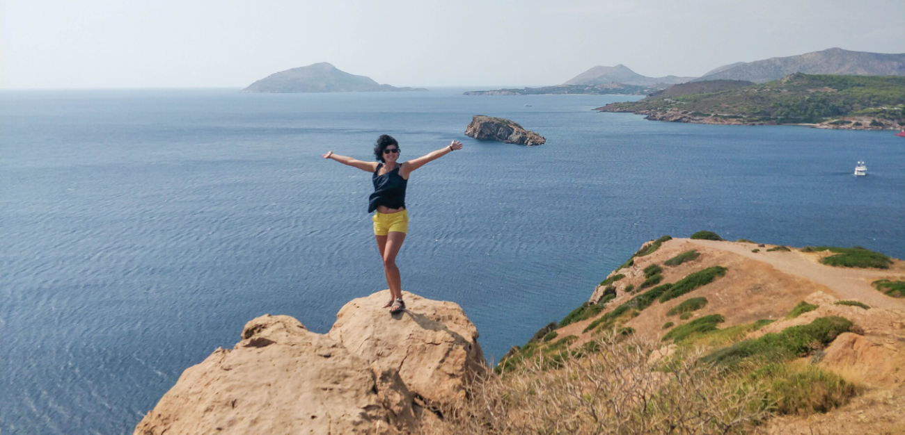 Student stands on a rock with the Mediterranean behind them.