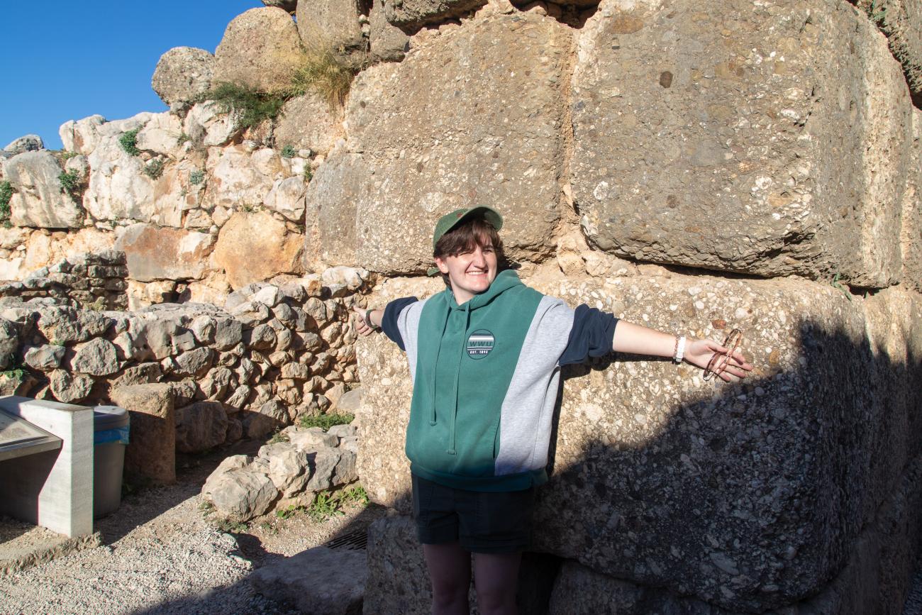 Lena with their arms spread to show the size of the Acrocorinth blocks