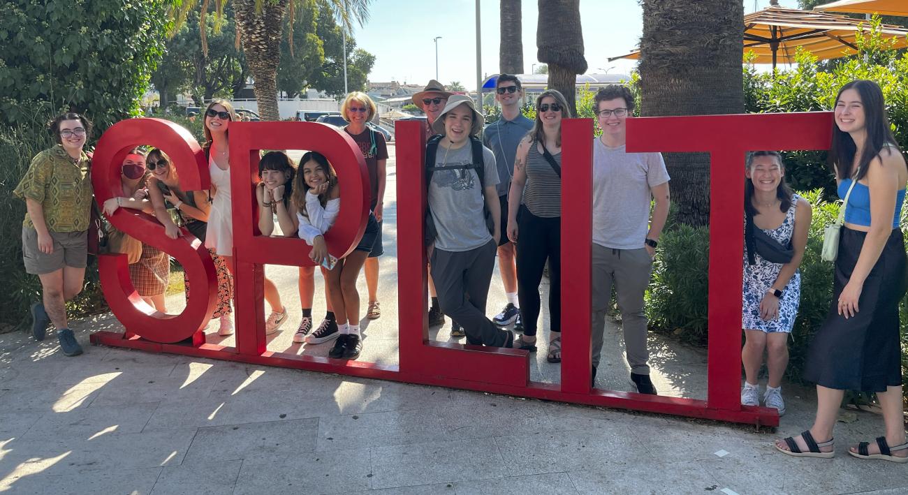  A group photo of Honors students in Split, Croatia next to a large red sculpture of the town's name.