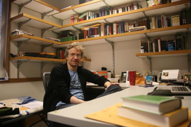 Dr. Goldman sitting in his office surrounded by shelves of books.